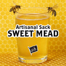 Glass of artisanal sweet mead with bees on a honeycomb background