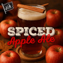Glass of spiced apple ale with cinnamon sticks, surrounded by apples on a warm-toned background.