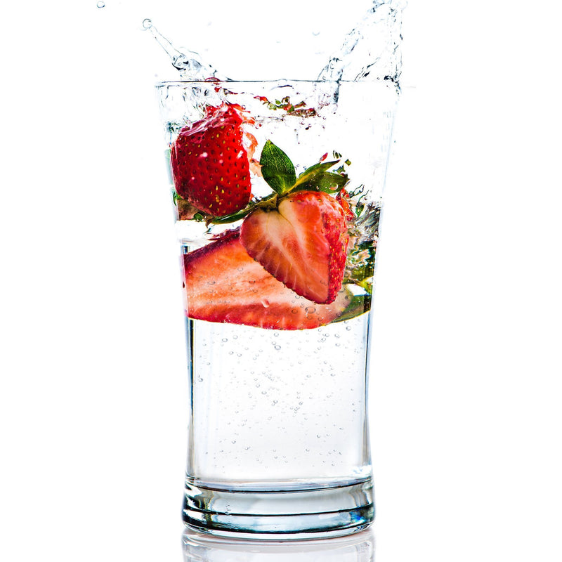 A vibrant glass of Strawberry Hard Seltzer with fresh strawberries beside it.