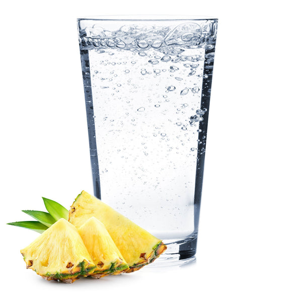 A glass of Pineapple Hard Seltzer with golden pineapple slices on the side.