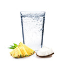 A tropical glass of Pina Colada Hard Seltzer with pineapple and coconut chunks beside it.
