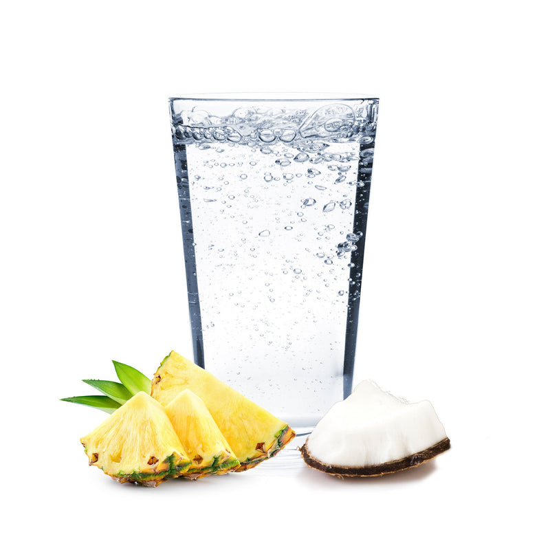 A tropical glass of Pina Colada Hard Seltzer with pineapple and coconut chunks beside it.