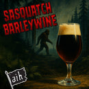 Glass of dark beer with Sasquatch Barleywine text and a silhouette of a bigfoot in a forest.