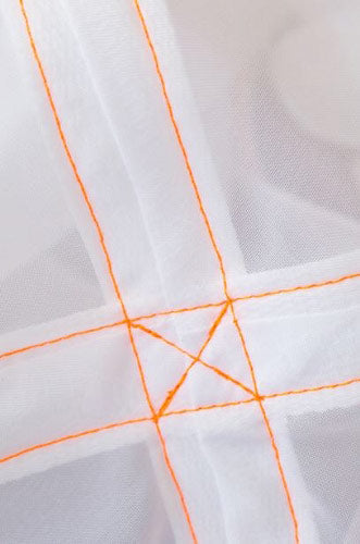 Close-up of white fabric with orange stitching