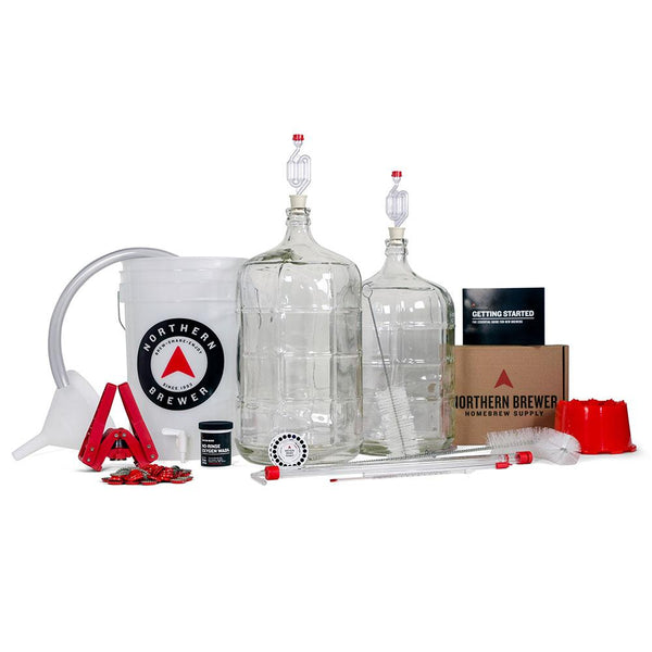 Two glass carboys with airlocks, a fermentation bucket, bottle capper with caps, racking cake, recipe kit, tubing, carboy brush, beer recipe kit, and carboy drier